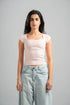 Woman wearing a light pink top and light blue jeans against a gray background