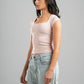 Woman wearing a light pink top and light blue jeans on a gray background
