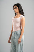 Woman wearing a light pink top and light blue jeans on a gray background