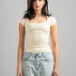 Woman wearing a white top and light blue jeans against a gray background