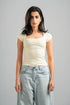 Woman wearing a white top and light blue jeans against a gray background
