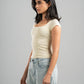 Woman wearing a beige top and light blue jeans against a gray background