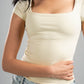 Woman wearing a beige top and light blue jeans against a gray background