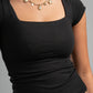 Person wearing a black top and gold necklace on a gray background