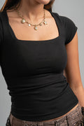 Person wearing a black top and gold necklace on a gray background
