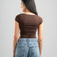 Woman wearing a brown top and blue jeans against a gray background