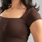 Woman wearing a brown top against a neutral background