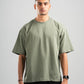 Man wearing a green t-shirt and black pants against a gray background