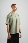 Man wearing a green t-shirt and black pants on a gray background
