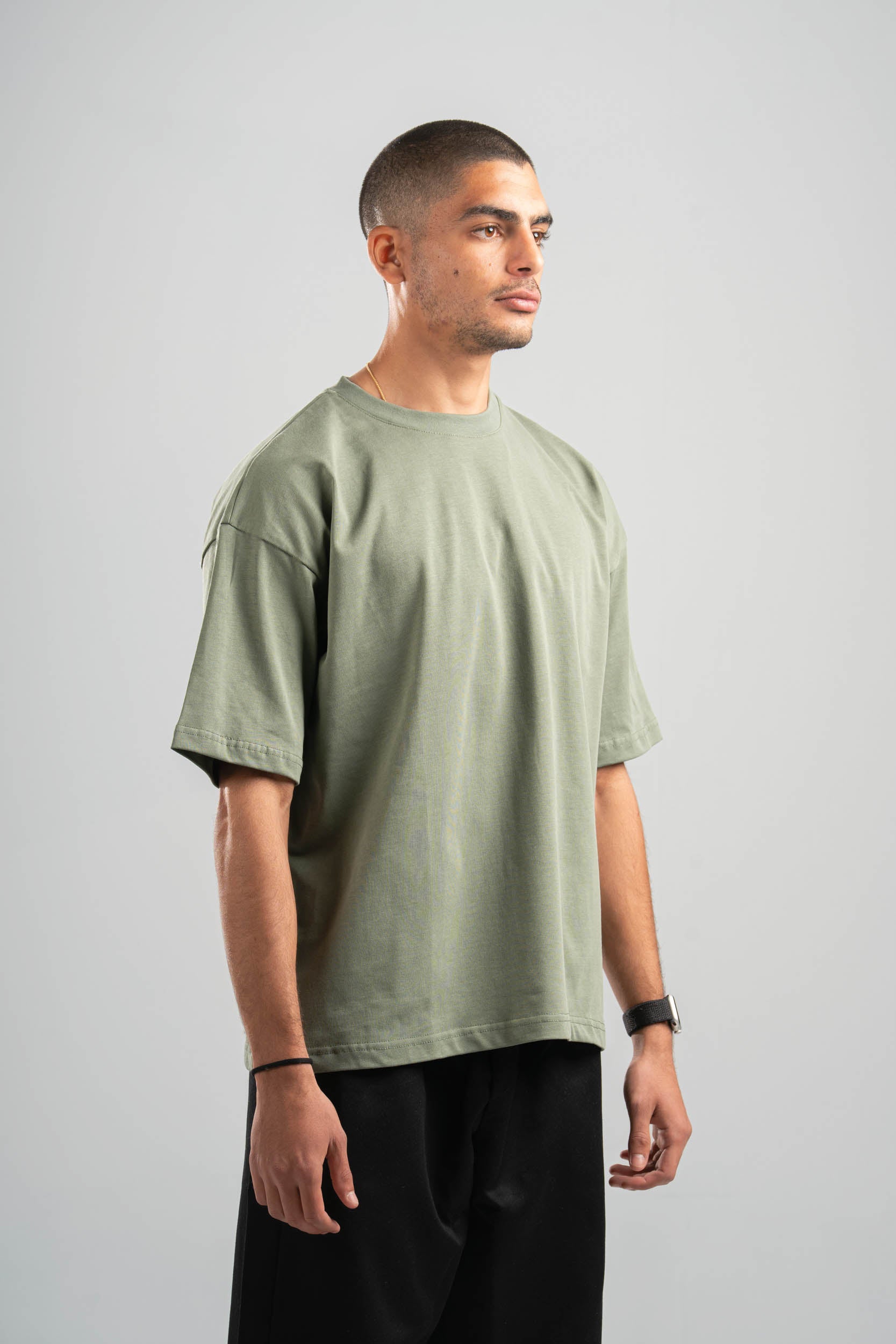 Man wearing a green t-shirt and black pants on a gray background