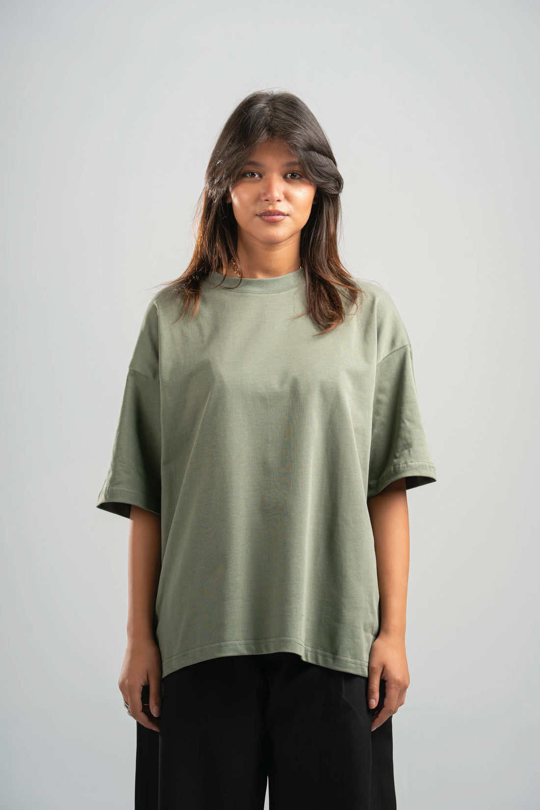 Two people wearing matching green t-shirts and black pants on a plain background