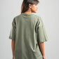 Person wearing a green oversized t-shirt on a plain background