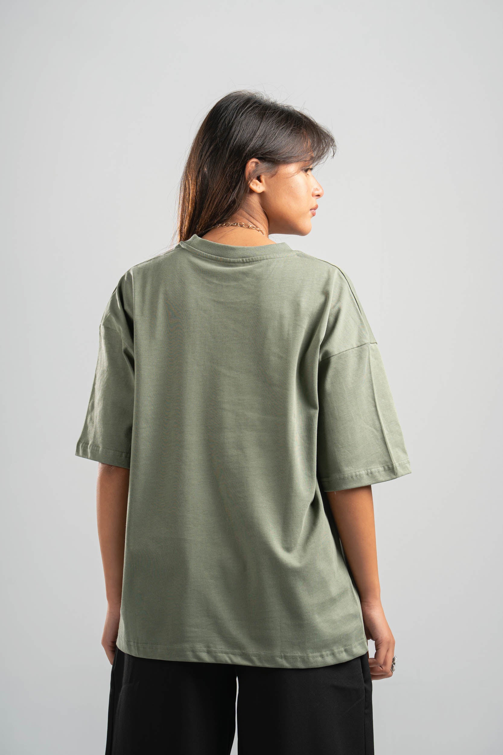 Person wearing a green oversized t-shirt on a plain background