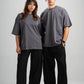 Two people wearing matching gray t-shirts and black pants on a white background