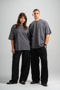 Two people wearing matching gray t-shirts and black pants on a white background