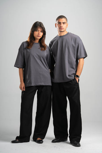 Two people wearing matching gray t-shirts and black pants on a white background
