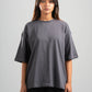 Person wearing a gray oversized t-shirt on a plain background