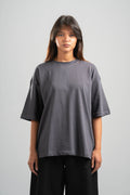 Person wearing a gray oversized t-shirt on a plain background