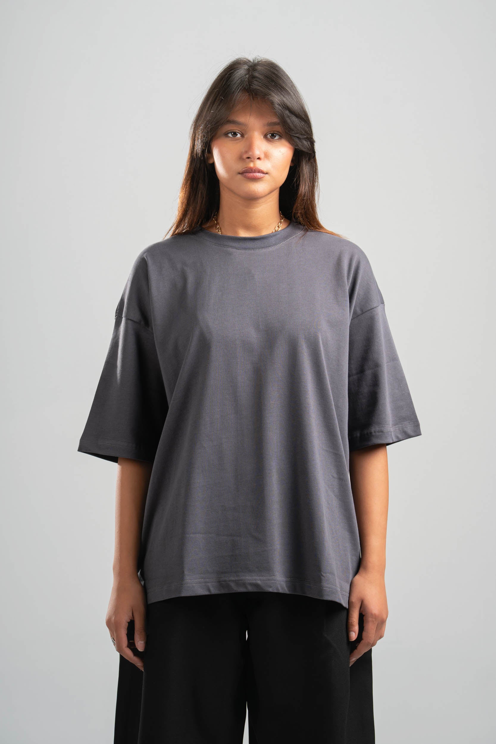 Person wearing a gray oversized t-shirt on a plain background