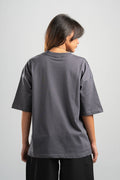Person wearing a gray oversized t-shirt on a plain background