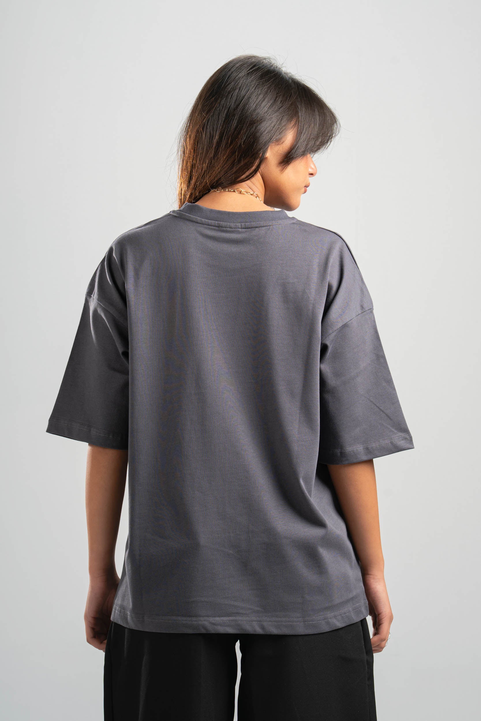 Person wearing a gray oversized t-shirt on a plain background