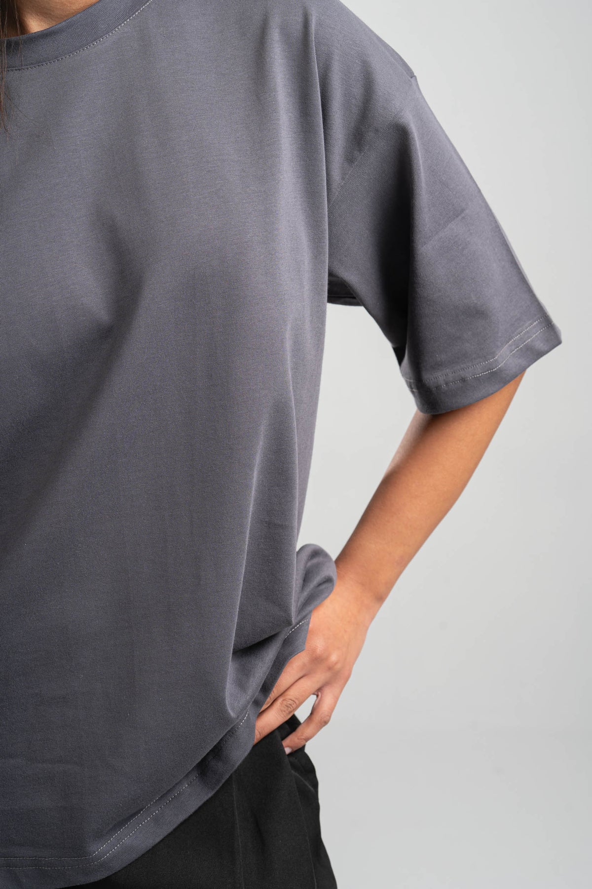 Person wearing a plain gray t-shirt against a light gray background