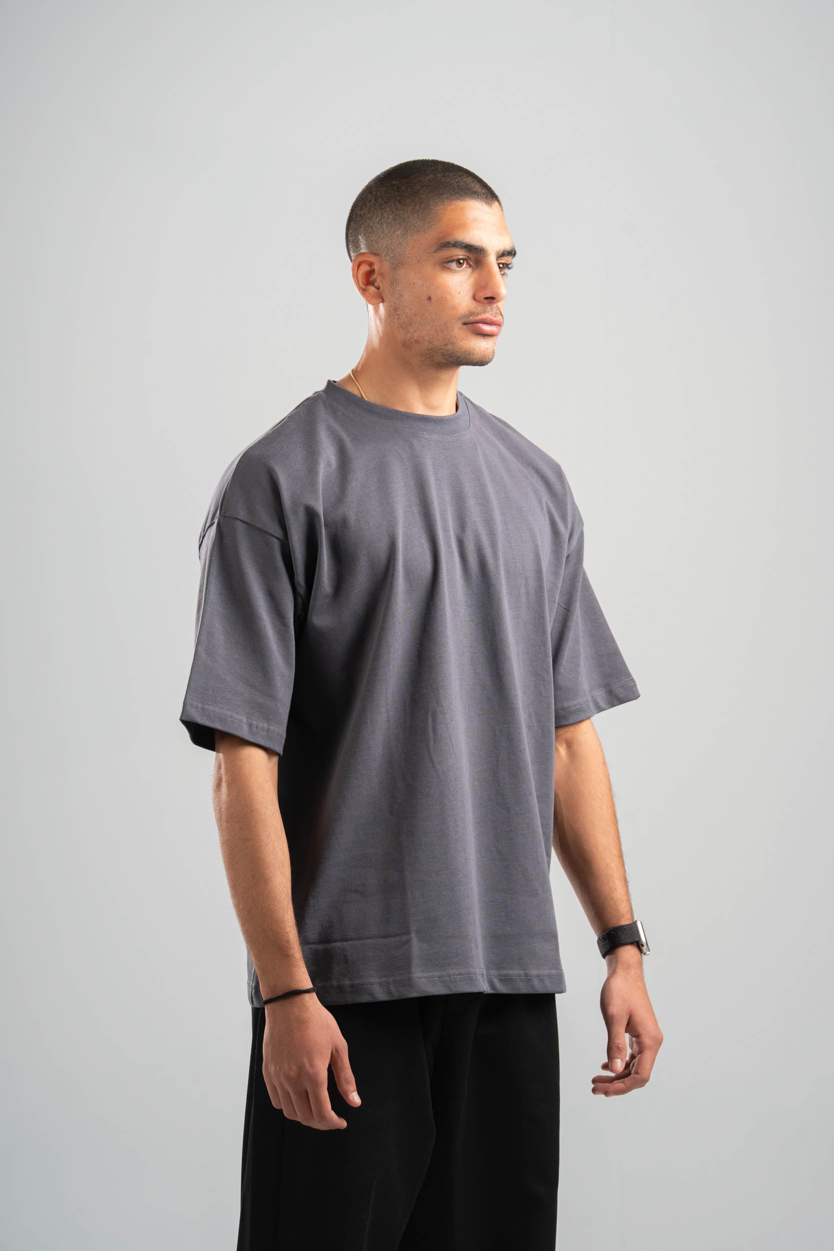 Man wearing a gray t-shirt and black pants on a light gray background