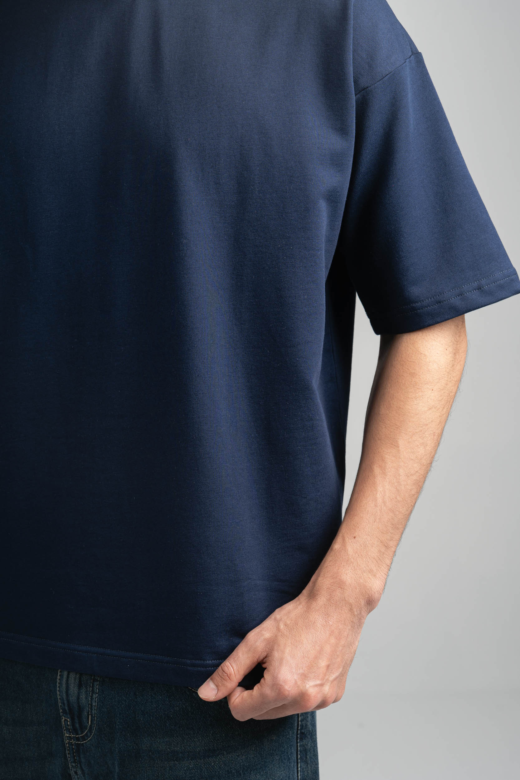 Person wearing a navy blue t-shirt on a gray background