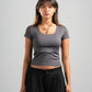 Woman wearing a gray t-shirt and black pants against a plain background