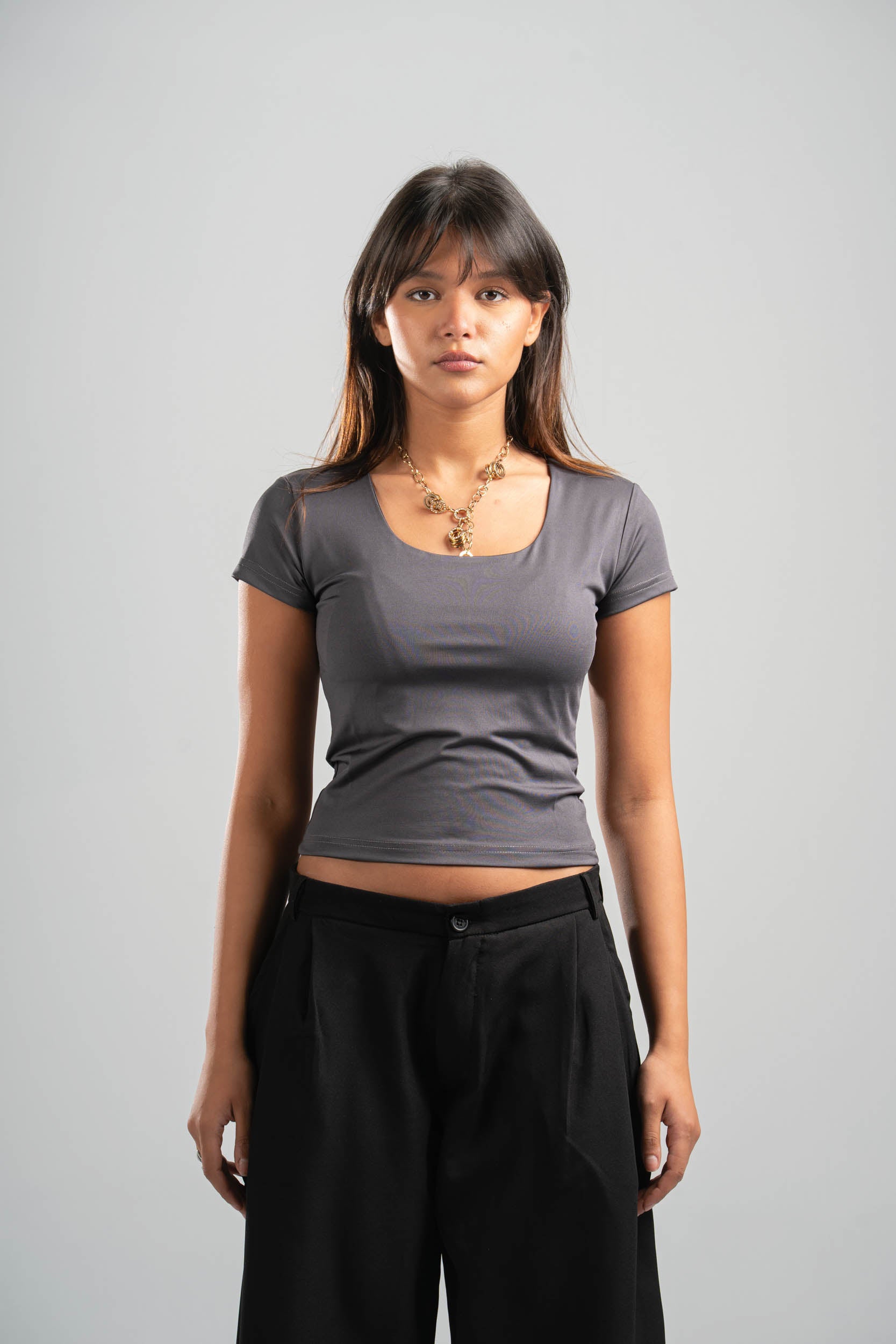 Woman wearing a gray t-shirt and black pants against a plain background