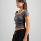 Woman wearing a gray crop top and black pants on a light gray background