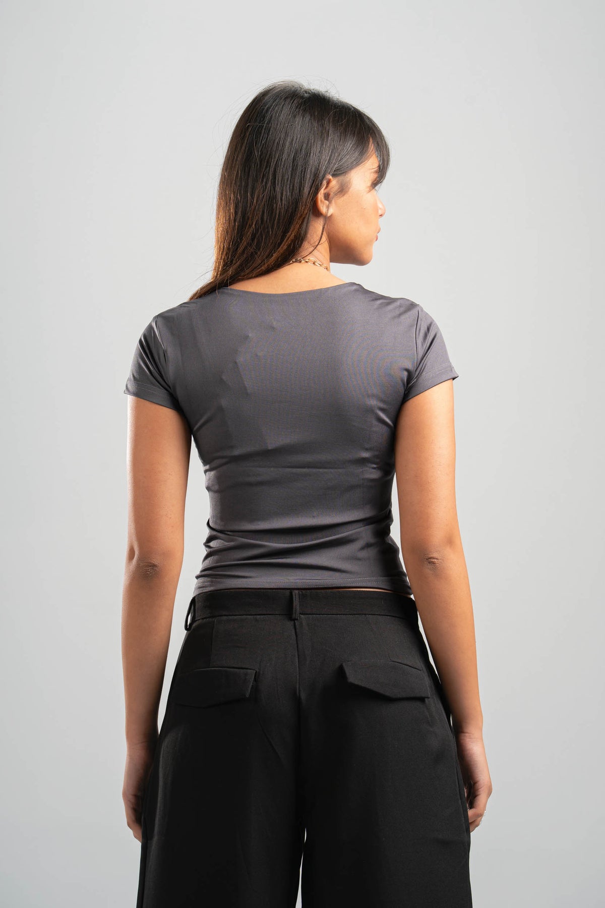 Person wearing a gray t-shirt and black pants against a light gray background