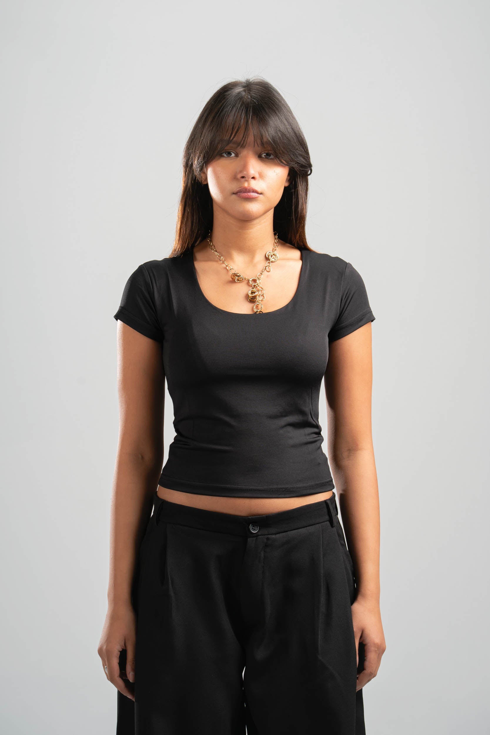 Woman wearing a black t-shirt and black pants on a gray background