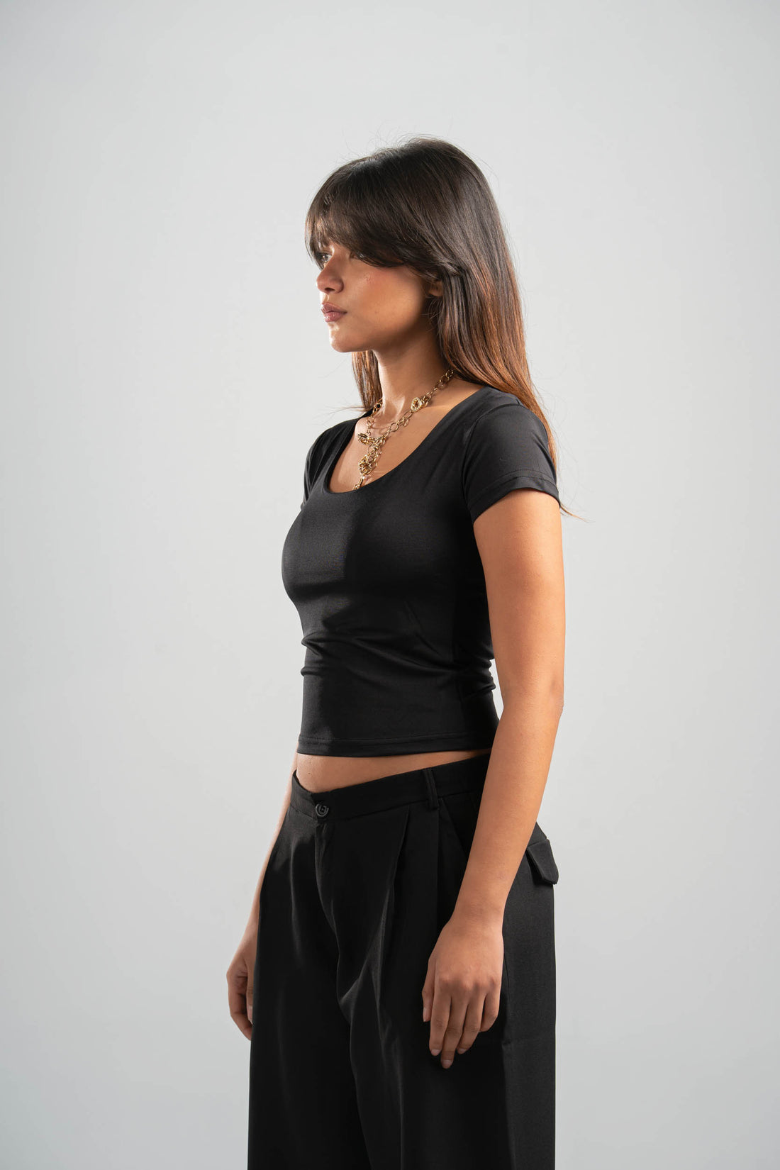 Woman wearing a black t-shirt and black pants on a gray background