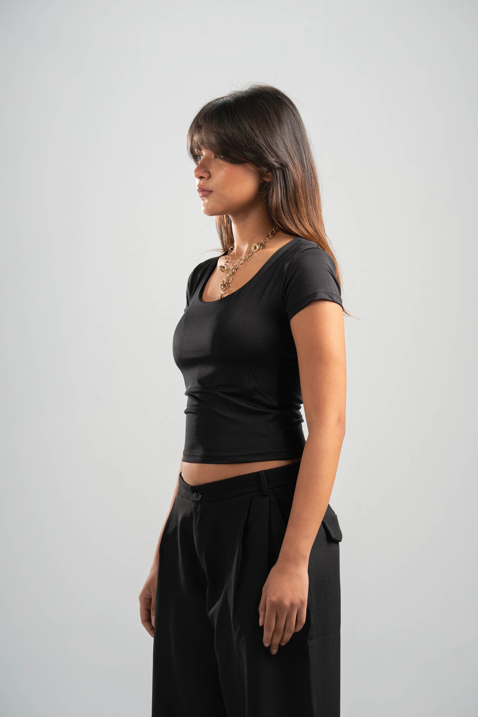 Woman wearing a black top and black pants on a light gray background