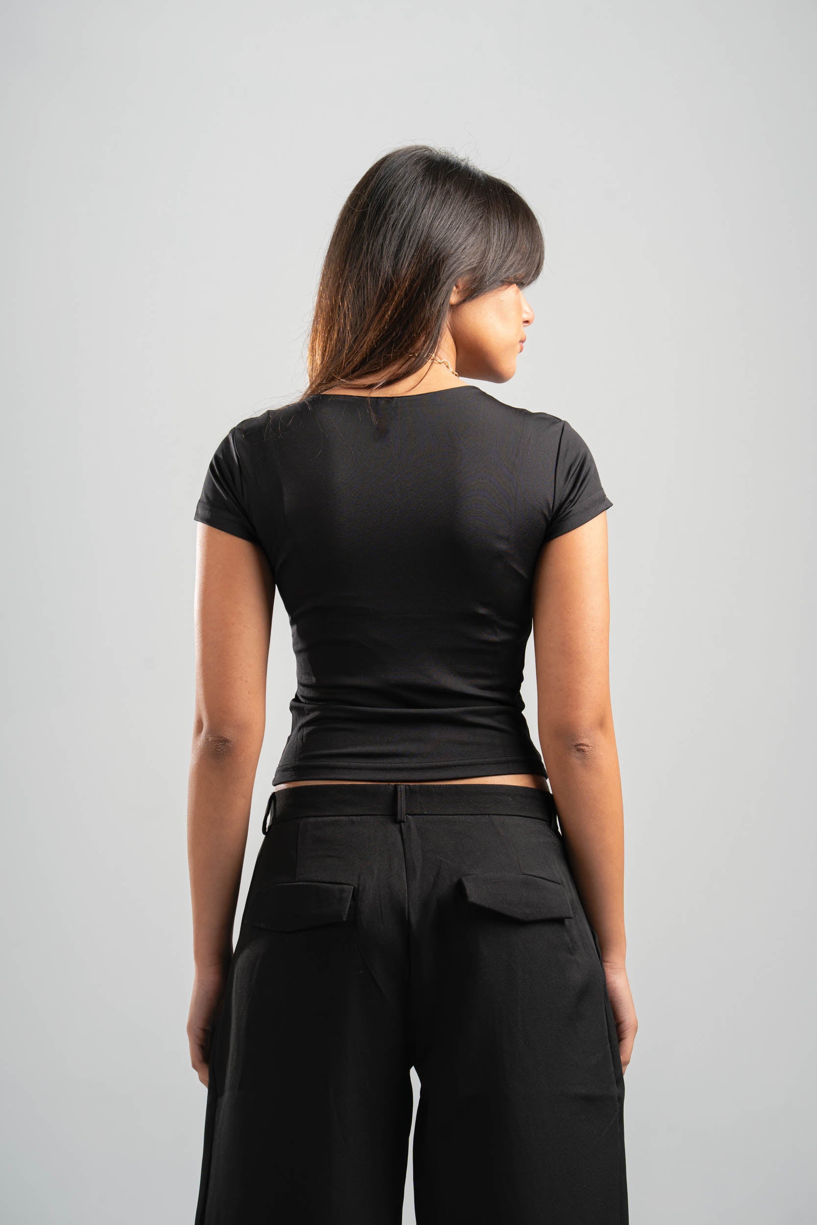 Person wearing a black t-shirt and black pants on a gray background