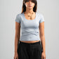 Woman wearing a light blue t-shirt and black pants on a gray background