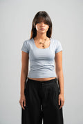 Woman wearing a light blue t-shirt and black pants on a gray background