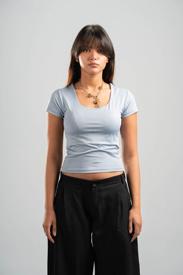Woman wearing a light blue t-shirt and black pants on a gray background