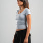 Woman wearing a light gray t-shirt and black pants on a plain background