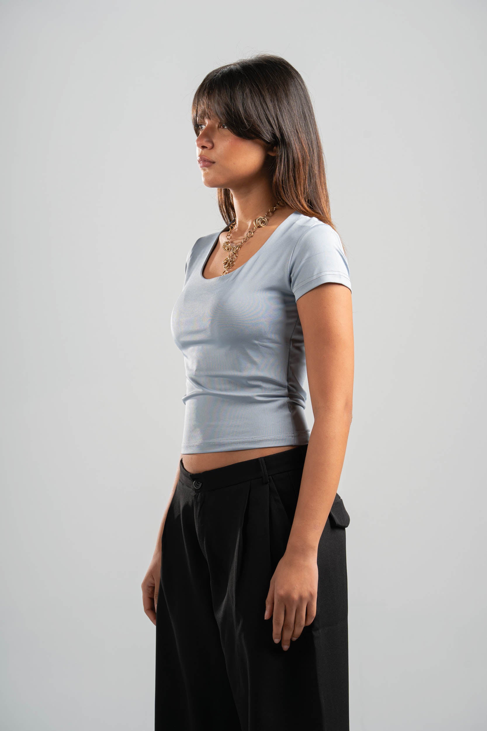 Woman wearing a light gray t-shirt and black pants on a plain background