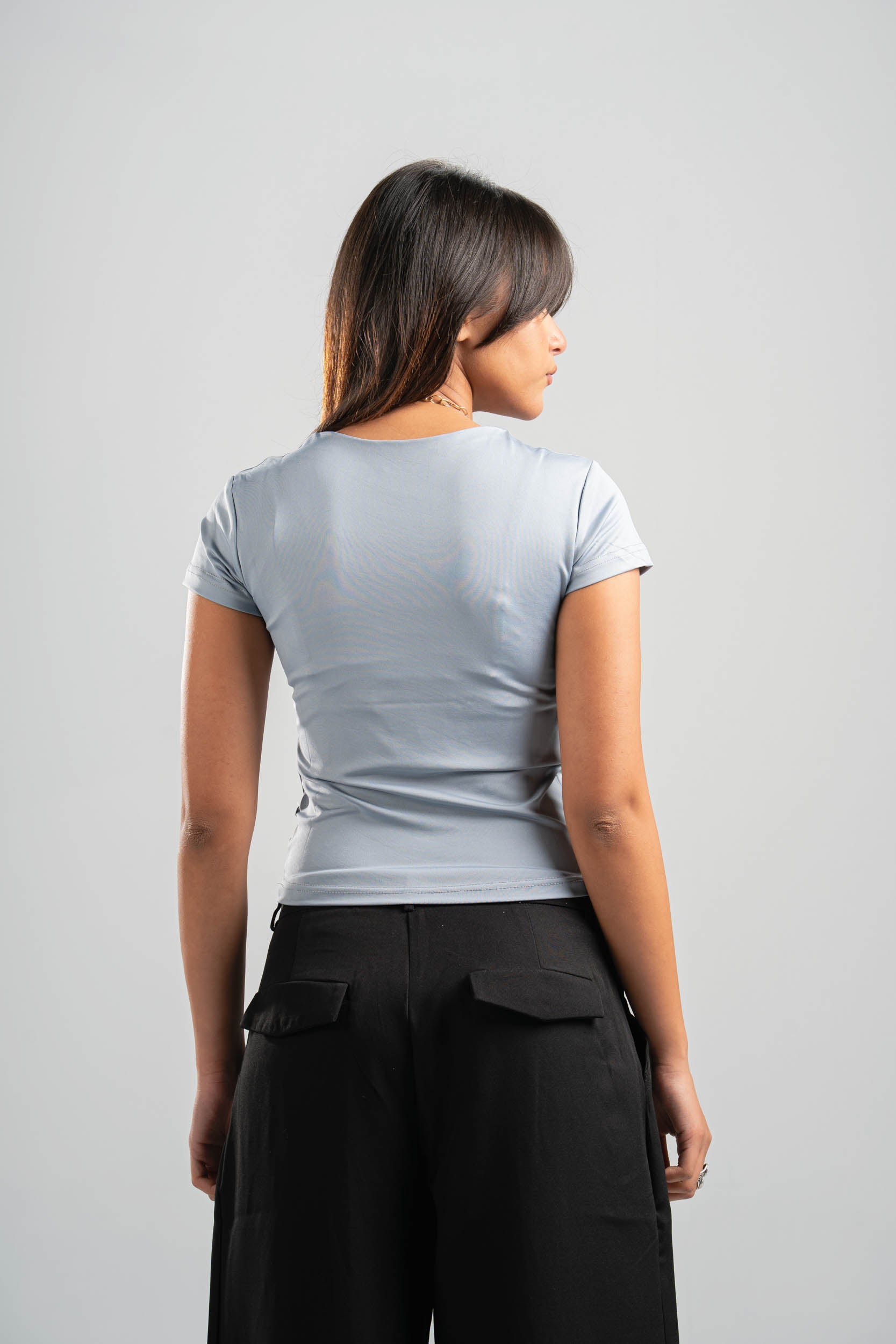 Woman wearing a gray t-shirt and black pants on a gray background