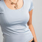Light blue top worn by a person on a gray background