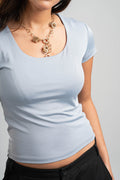 Light blue top worn by a person on a gray background