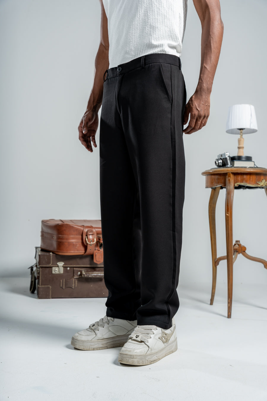 Person wearing black pants with a white background and vintage suitcases.