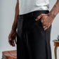 Person wearing black pants with a white shirt, standing next to a suitcase.
