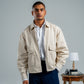 Man wearing a beige jacket over a white shirt with a gray background