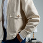 Person wearing a beige jacket with a neutral background