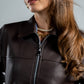 Woman wearing a brown leather jacket with a gray background