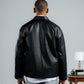 Man wearing a black leather jacket from behind on a plain background